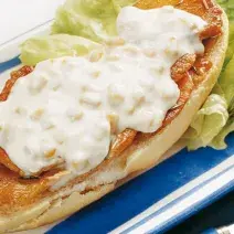 fotografia em tons de branco e azul tirada de uma bandeja azul com sanduiche com pedaços de lombo e creme branco por cima