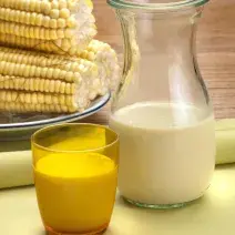 foto tirada de uma jarra com suco de milho e à frente um copo amarelo com a bebida