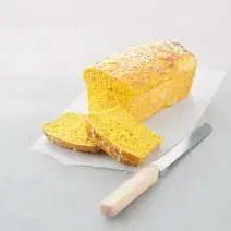 fotografia em tons de branco e amarelo tirada de um pão e duas fatias do mesmo e ao lado uma faca.