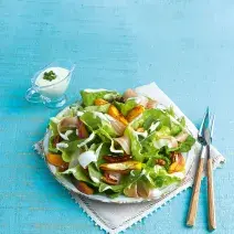 fotografia em tons de azul e branco de uma bancada azul vista de cima, ao centro um pano branco com um prato redondo que contém a salada.