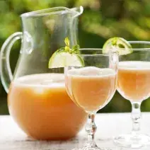 foto tirada de um jarra transparente com a bebida e à frente duas taças e ambas com a bebida
