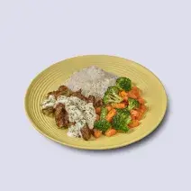 Fotografia em tons de amarelo em um fundo branco com um prato amarelo com arroz, legumes salteados e tirinhas de carne com molho de iogurte.