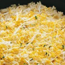 Uma panela comporta o arroz em tons amarelos.