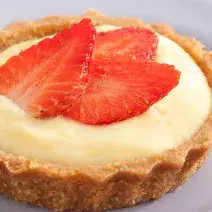 fotografia em tons de branco e vermelho tirada de um prato branco redondo com uma tortinha por cima.