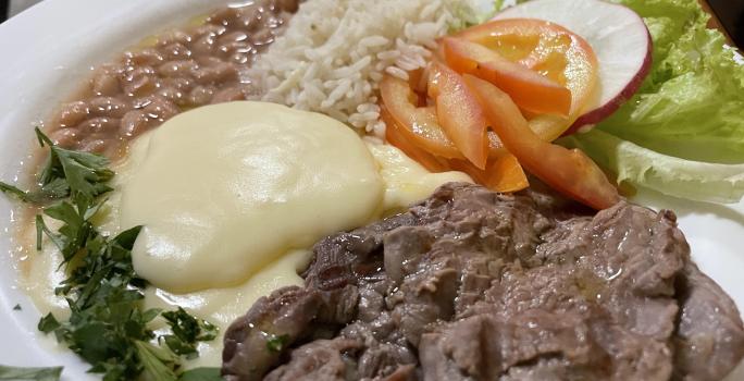 Foto da receita de Purê Francês. Observa-se um prato com um cremoso purê de batatas, acompanhado de arroz, feijão, iscas de carne e uma salada de tomate, rabanete e alface crespa.