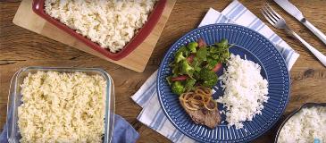 Como Fazer Arroz Soltinho Tela de vídeo mostra uma mesa com uma travessa de arroz branco, uma de arroz integral e um prato com arroz, bife e salada