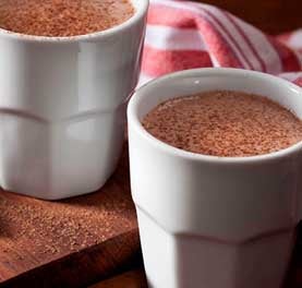Dois copos brancos com bebida de chocolate polvilhada com chocolate em pó. Dois copos brancos com bebida de chocolate polvilhada com chocolate em pó.