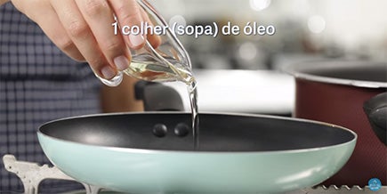 Pessoa derrama um fio de olho de um pote pequeno em uma frigideira