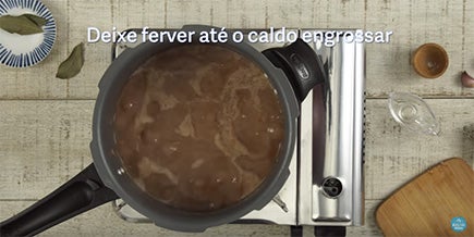 Foto de cima de panela aberta com feijão cozido e água borbulhando