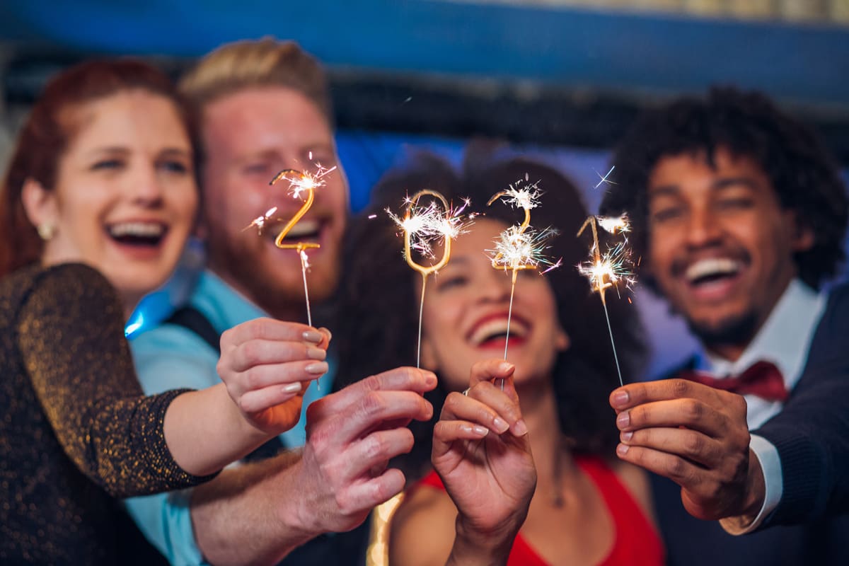 Ceia de Ano Novo: Quatro pessoas rindo com um objeto luminoso na mão