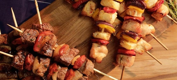 Vários espetinhos de carne e frango sobre uma tábua de madeira. Vários espetinhos de carne e frango sobre uma tábua de madeira.
