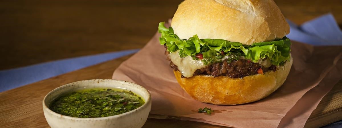 Capa: Dia do hambúrguer Receitas de hambúrguer caseiro: Molho em uma tigela à esquerda, à direita um hambúrguer , os dois em cima de uma tábua de mad