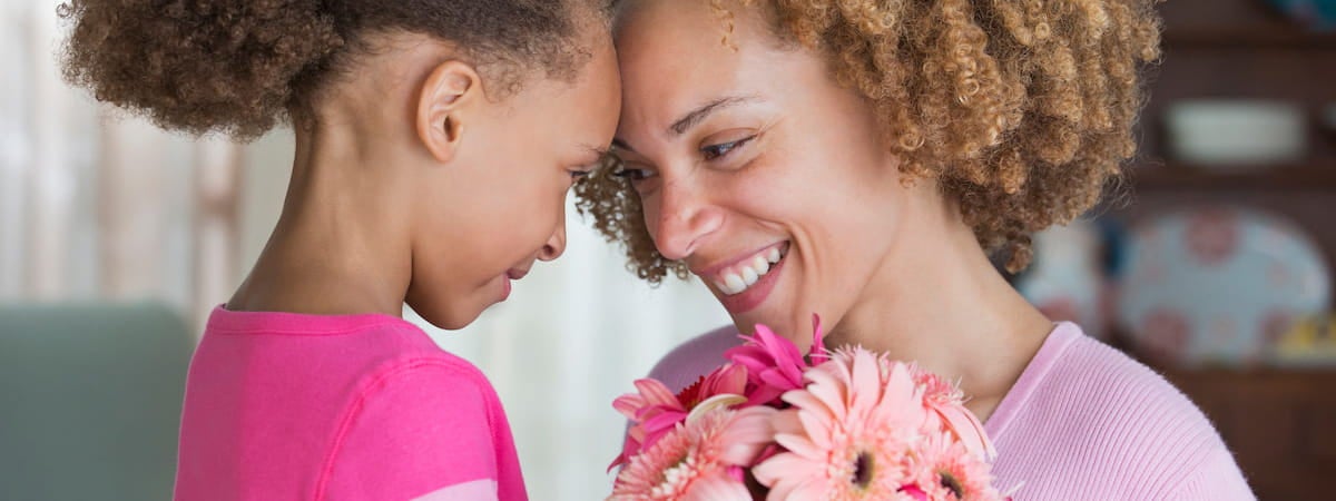 Capa: Dia das mães Dia das Mães: Mãe e filha bem próximas encostando a testa uma na outra, sorrindo com uma flor no meio