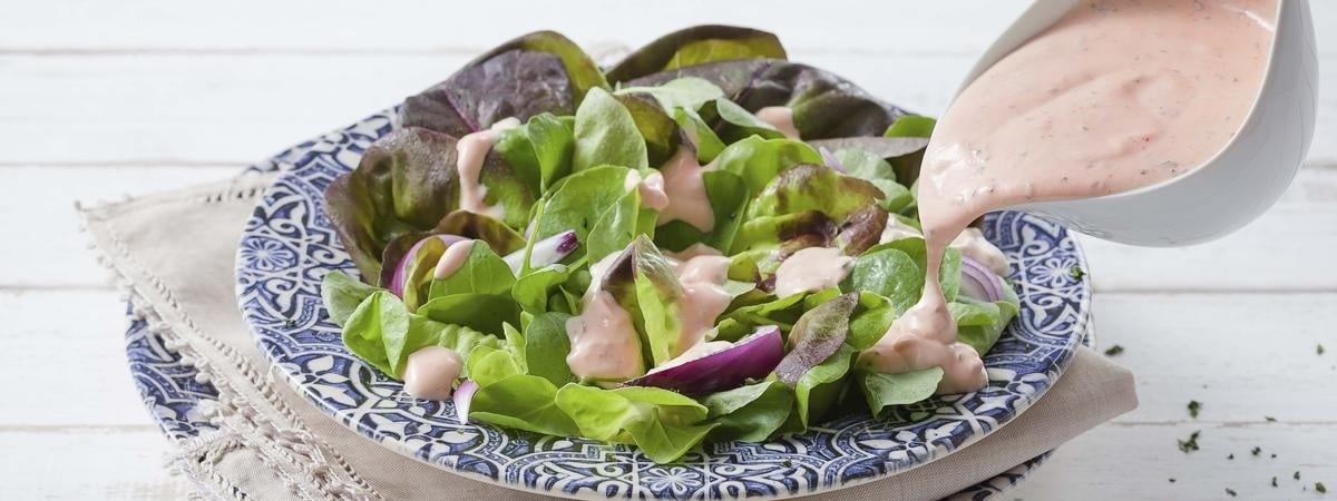 Capa: Molho Rosê Molho rosê sendo derramado em uma salada em cima de um prato