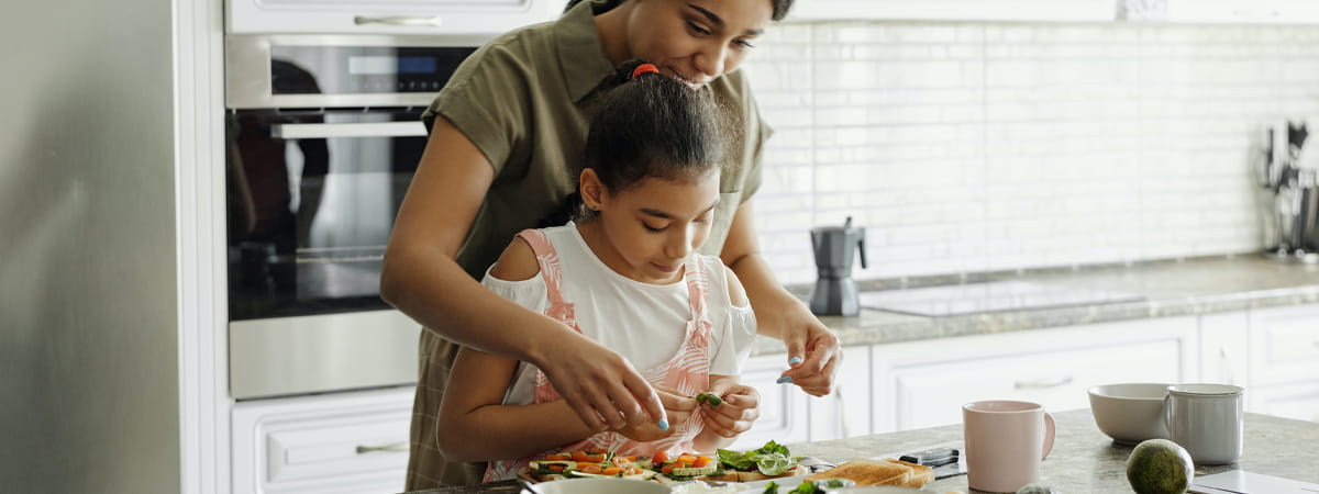 Capa: Almoço para o dia das mães Almoço de Dia das Mães: Mulher negra adulta na cozinha ajudando criança negra a cozinhar