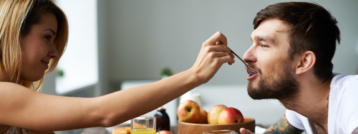 Capa: Café da manhã romântico Café da Manhã Romântico: Mulher à esquerda colocando uma colher com comida na boca de um homem à direita