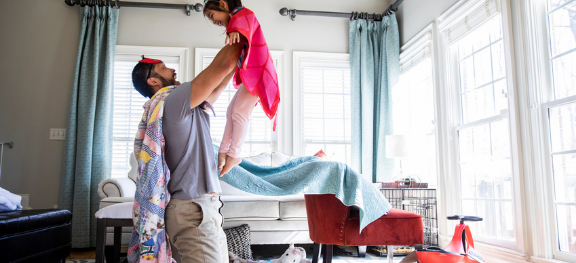 Pai e filha brincando. Ele carrega a menina. Os dois usam lençóis como se fosse capas. Pai e filha brincando. Ele carrega a menina. Os dois usam lençóis como se fosse capas.