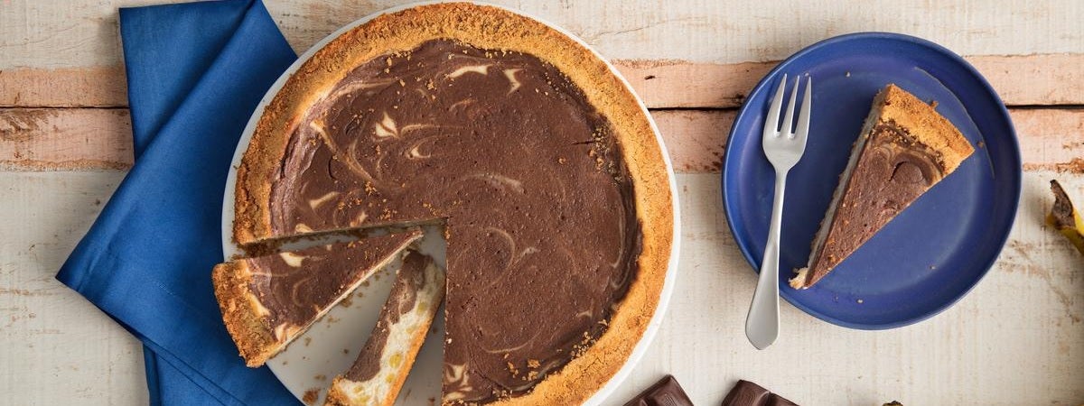 Capa: Sobremesas Torta de chocolate com dois pedaços cortados sobre um pano azul. À direita, pedaço de torta sobre um prato com um garfo ao la