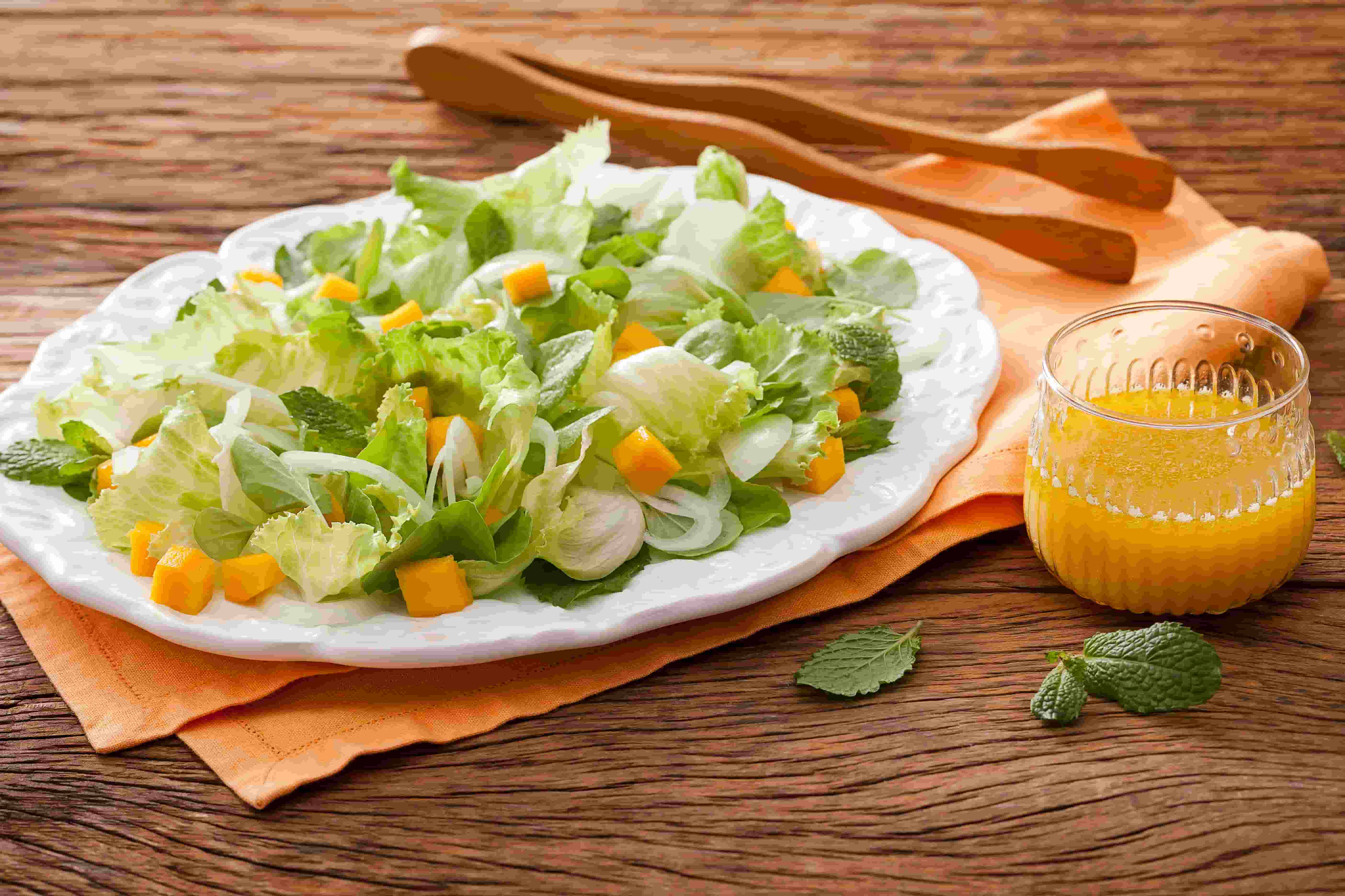 foto em tons de laranja, verde e marrom de uma bancada vista de frente, contém um prato com a salada e pedaços de manga