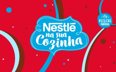 Montagem em azul e vermelho, com alguns símbolos e curvas com a frase NESTLÉ NA SUA COZINHA em branco no centro e o logo da marca