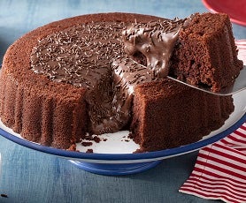 Imagem de um prato com um bolo de chocolate com brigadeiro e uma fatia sendo tirada