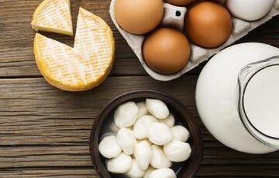 Ovos em bandeja e três tipos de queijo em uma tábua. A imagem representa os alimentos ricos em K2.