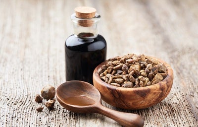Frasco de vidro com própolis, tigela de madeira com pedaços de própolis e colher de madeira sobre superfície rústica.