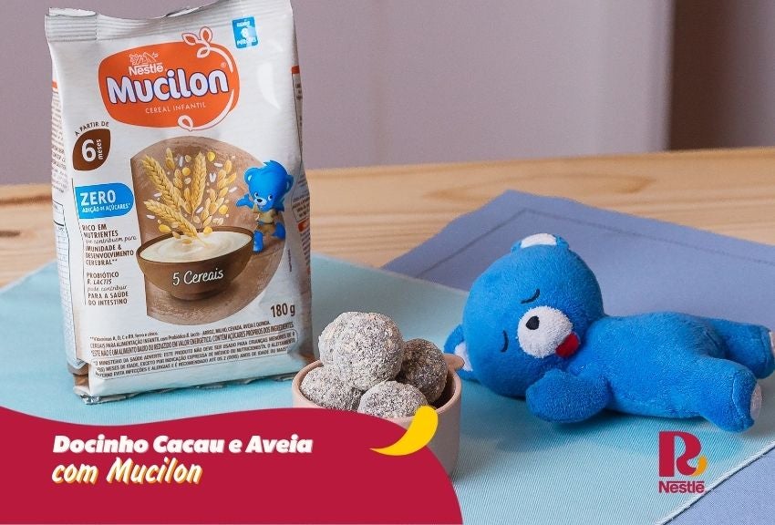 Docinho de cacau e aveia com Mucilon em tigela, com embalagem ao fundo e mascote azul ao lado