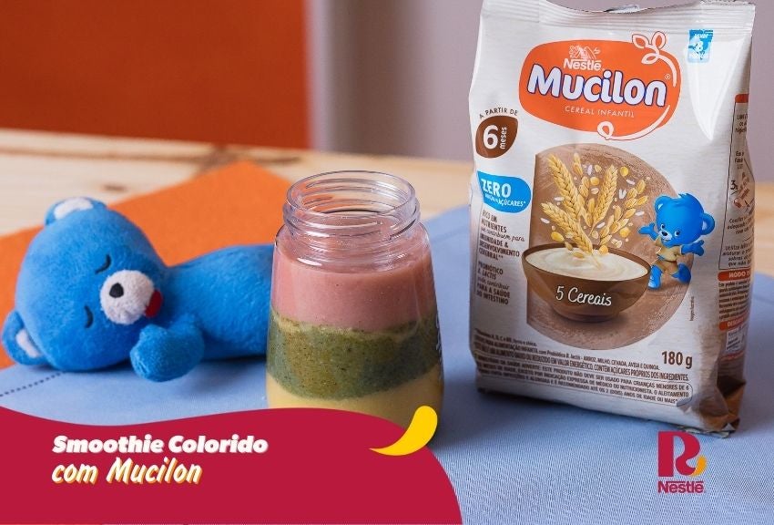 Smoothie colorido com Mucilon em pote, com camadas, embalagem ao fundo e mascote azul ao lado