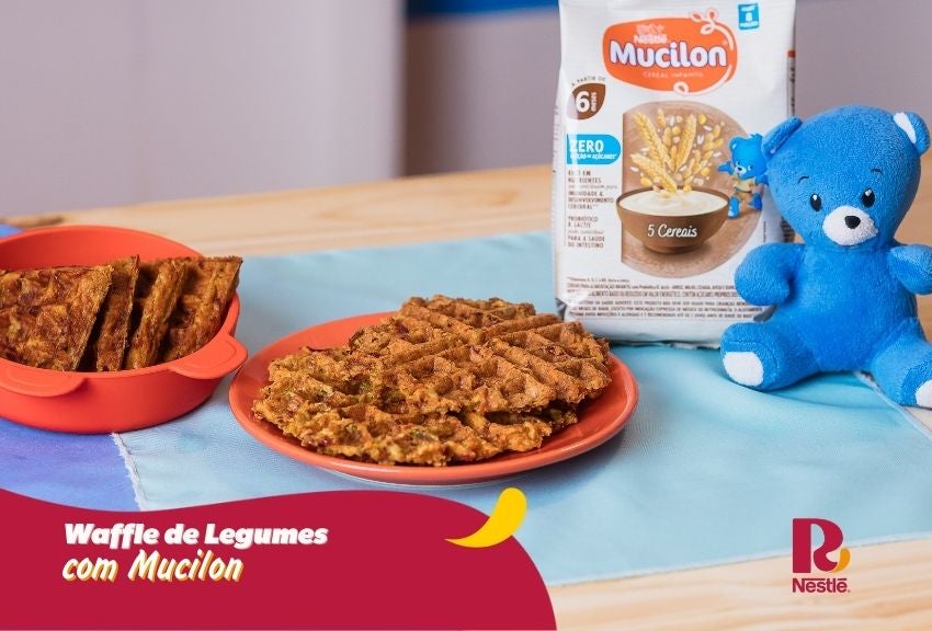 Waffle de legumes com Mucilon, servido em prato, com embalagem ao fundo e mascote azul ao lado