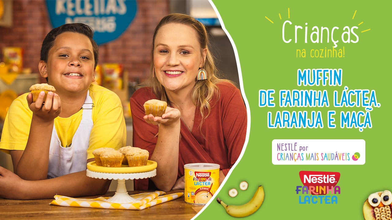 Criança e mulher seguram muffins de Farinha Láctea, laranja e maçã em cenário de culinária infantil.
