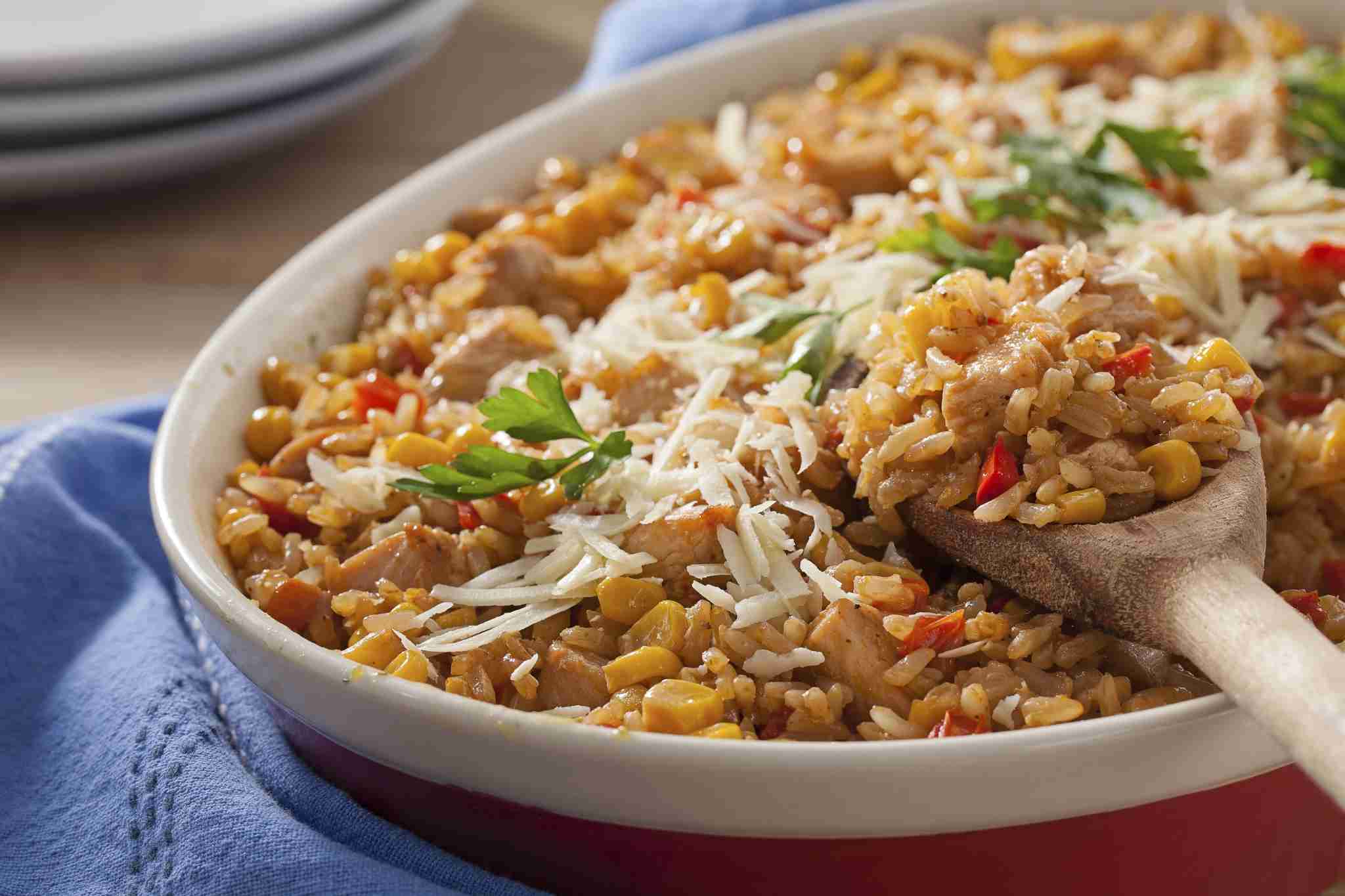 Travessa com arroz temperado com frango, milho, tomate e queijo ralado.