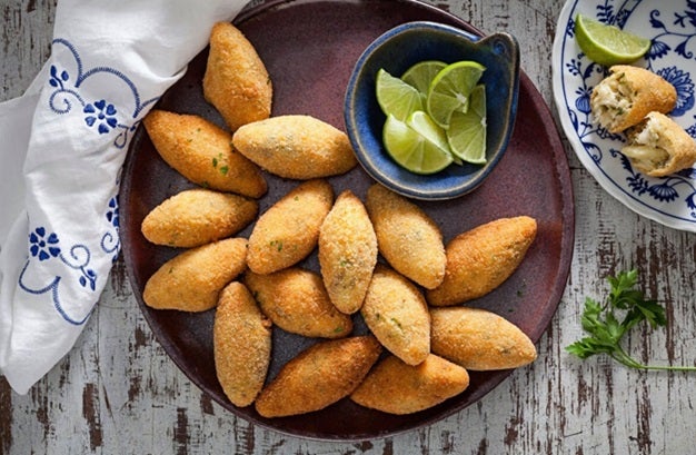 Bolinho de bacalhau com pedaços de limão ao lado.