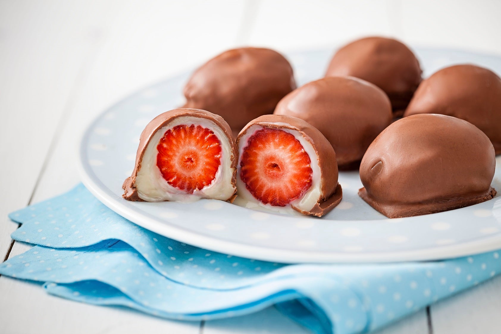 Imagem de bombons de morango e um bombom cortado ao meio mostrando o morango e o recheio.