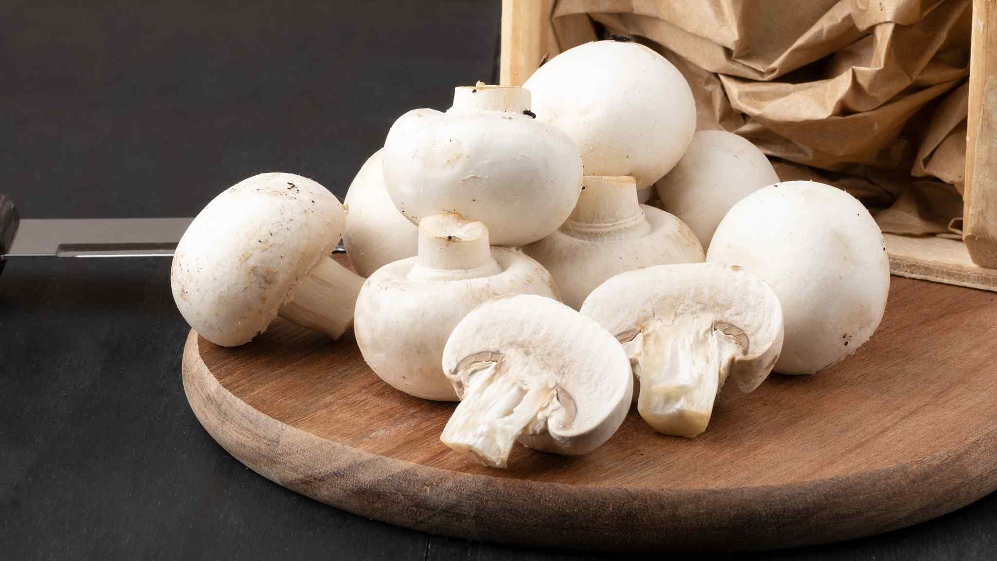 Imagem de cogumelos paris sobre uma tábua de madeira.