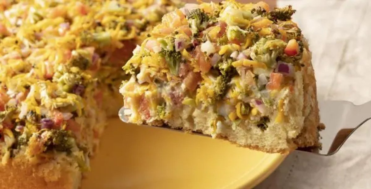 Imagem de uma torta de legumes com brócolis com uma fatia na espátula.