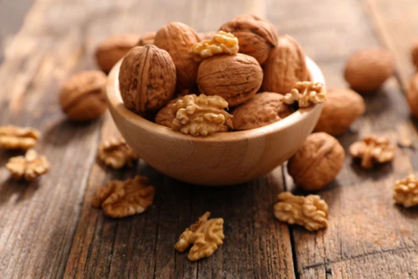 Bowl com nozes em cima de uma superfície de madeira.