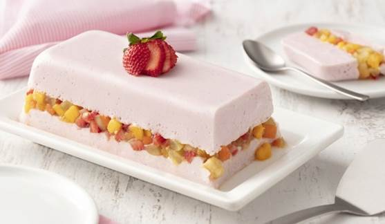 Sobremesa de gelatina com salada de frutas e morango em prato retangular.