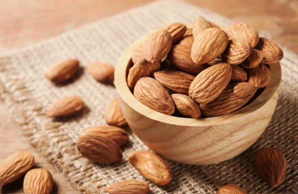 Bowl com amêndoas em cima de uma superfície de madeira.
