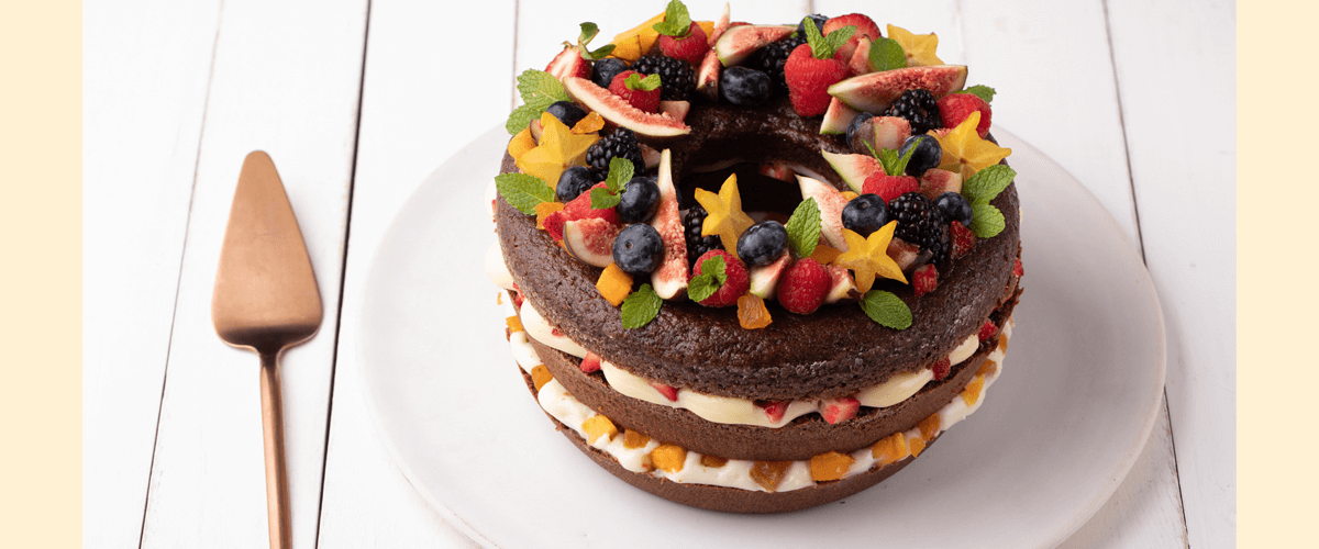 Bolo de aniversário coberto com frutas vermelhas e gotas de chocolate na  toalha de mesa branca conceito moderno de padaria