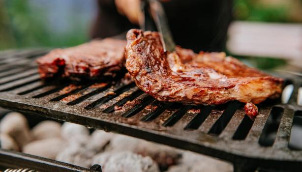 Cortes de Carne Bovina: uma pessoa colocando carne na grelha