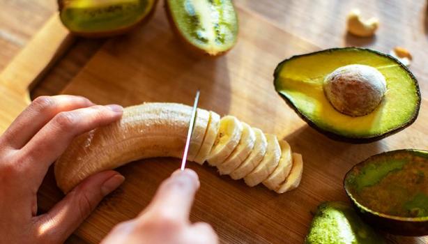 Safra de Março: uma pessoa cortando uma banana, com um abacate cortado do lado