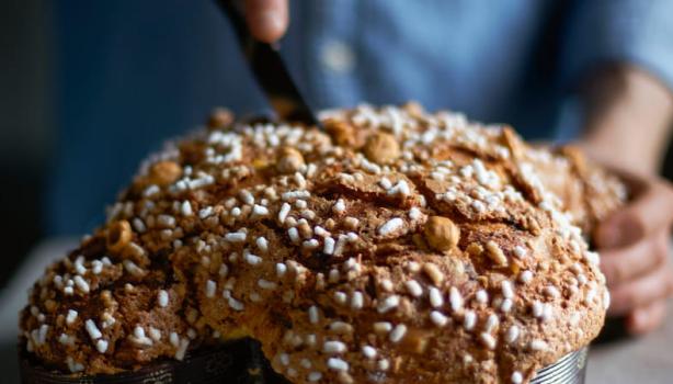 Colomba pascal sendo cortada por uma pessoa em cima de uma mesa