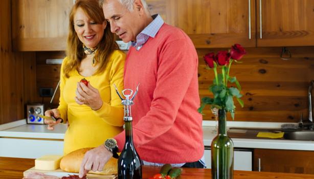 Jantar Romântico: Uma mulher branca idosa à esquerda e um homem branco idoso à direita, ambos cozinhando