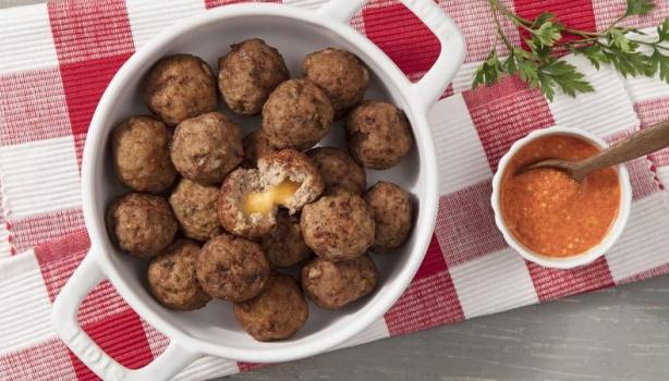 Panela com vários bolinhos de carne moída recheados com queijo. À direita um molho e, abaixo, um pano xadrez (Vermelho e bran