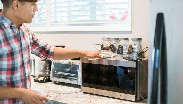 Homem limpando o micro-ondas em sua cozinha