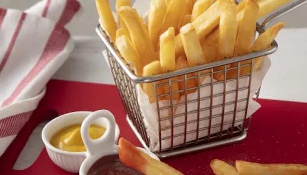 Fotografia em tons de vermelho de uma bancada branca, ao centro uma tábua vermelha com uma cestinha com batatas fritas dentro