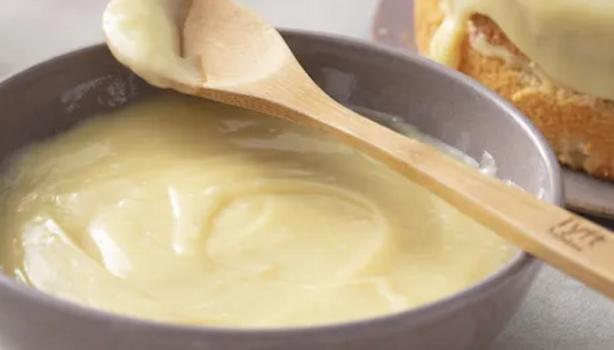 Ganache de Chocolate Branco em uma tigela branca com uma colher de madeira em cima