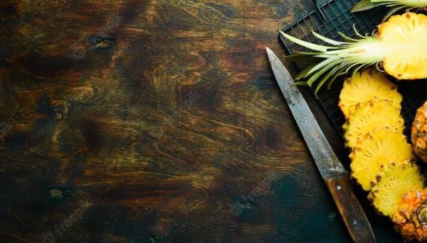 Abacaxis cortados em cima de uma bandeja de grade com uma faca ao lado em cima de uma mesa