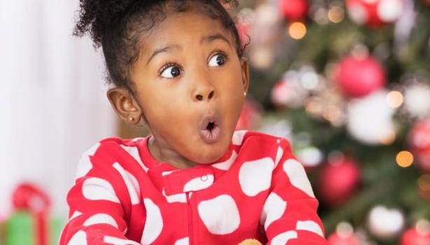 Presentes de Natal: menina negra com cara de surpresa, com a mão em um presente
